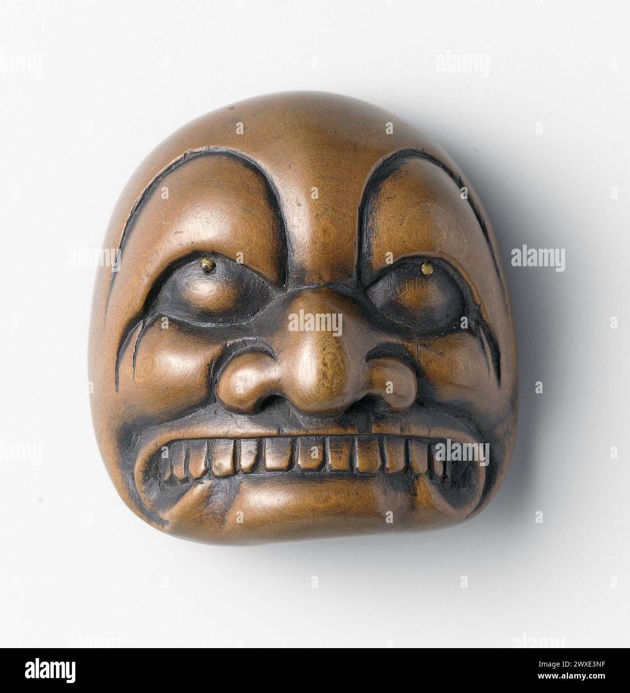 Japanisches Holznetzwerk aus der Edo-Zeit. Maske eines Dämons. Signiert „ransen“. 1800-1850 A'netsuke' ist eine Miniaturskulptur aus Japan des 17. Jahrhunderts. Anfangs ein einfach geschnitzter Knopfverschluss an den Kordeln der an'inro'Box (kleines Etui, das an einem Flügel hängt, der einen Kimono hält. Stockfoto