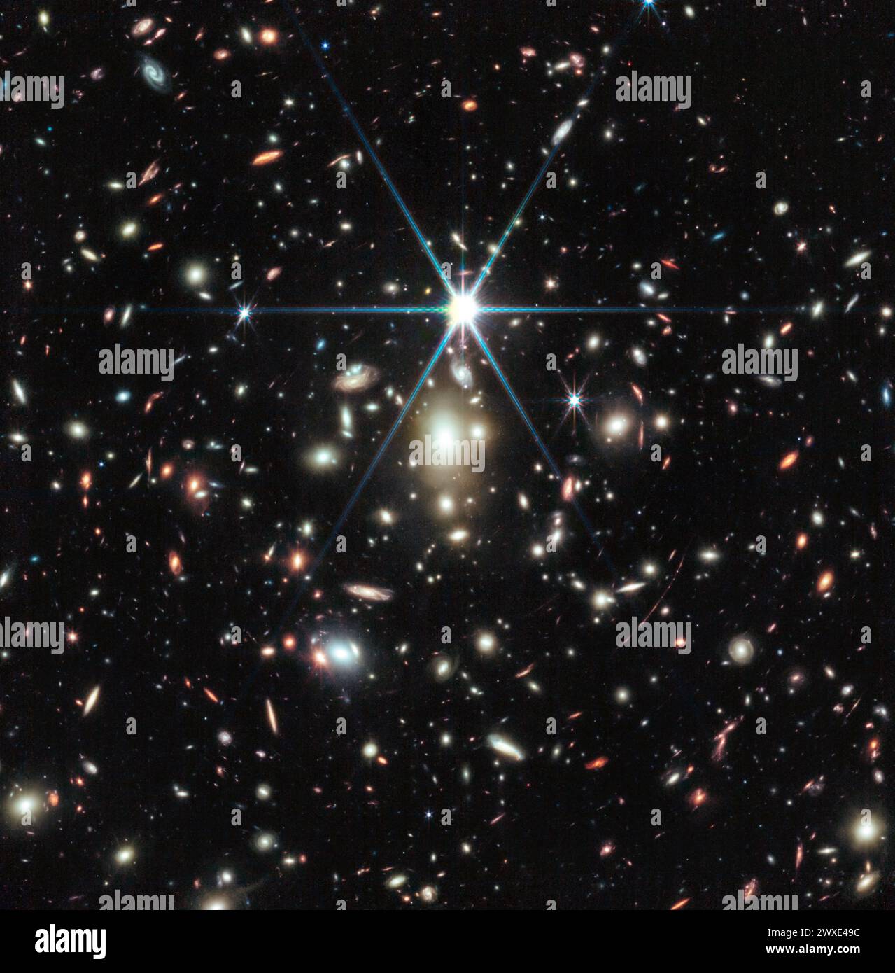 Dieses Bild des James Webb Weltraumteleskops der NASA zeigt einen massereichen Galaxienhaufen namens WHL0137-08 und enthält die am stärksten vergrößerte Galaxie, die in den ersten Milliarden Jahren des Universums bekannt ist: Den Sonnenaufgangsbogen und innerhalb dieser Galaxie den am weitesten entfernten Stern, der je entdeckt wurde. In diesem Bild erscheint der Sonnenaufgangsbogen als roter Streifen direkt unter der Beugungsspitze in der 5-Uhr-Position. Quelle: NASA, ESA, CSA, Dan Coe (STScI/AURA für ESA, JHU), Brian Welch (NASA-GSFC, UMD), mit Bildverarbeitung durch Zolt G. Levay Stockfoto