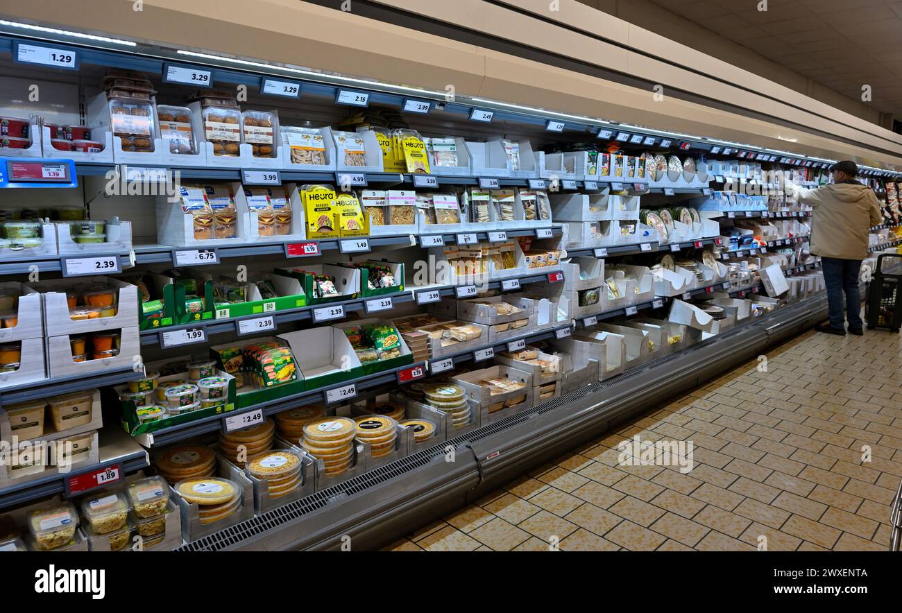 Regale mit Snacks und verzehrfertigen Lebensmitteln, die sich über den langen Gang des Lidl Supermarktes erstrecken Stockfoto