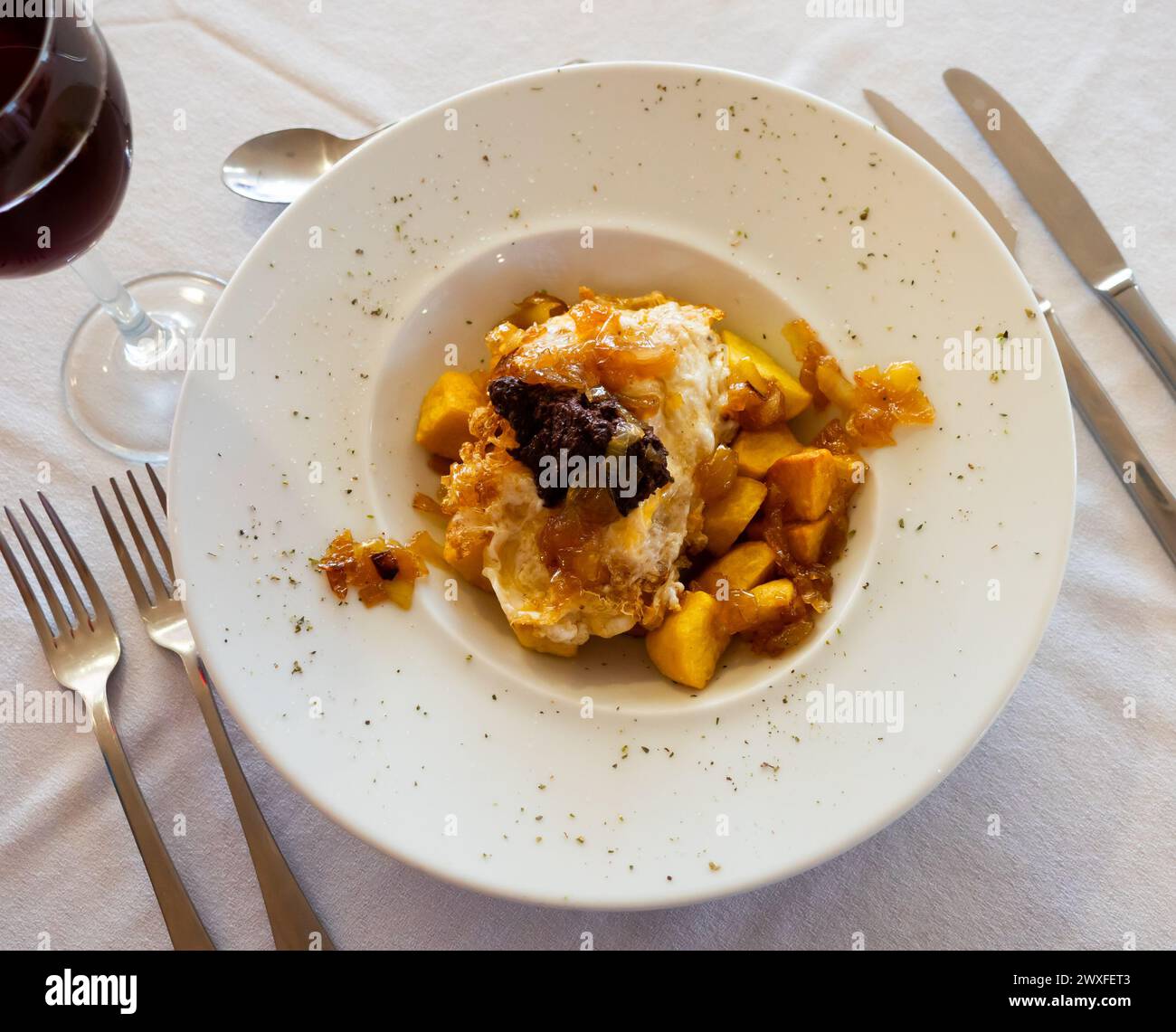 Spanische traditionelle Küche, Huevos Rotos con morcilla auf einer weißen Keramikplatte Stockfoto