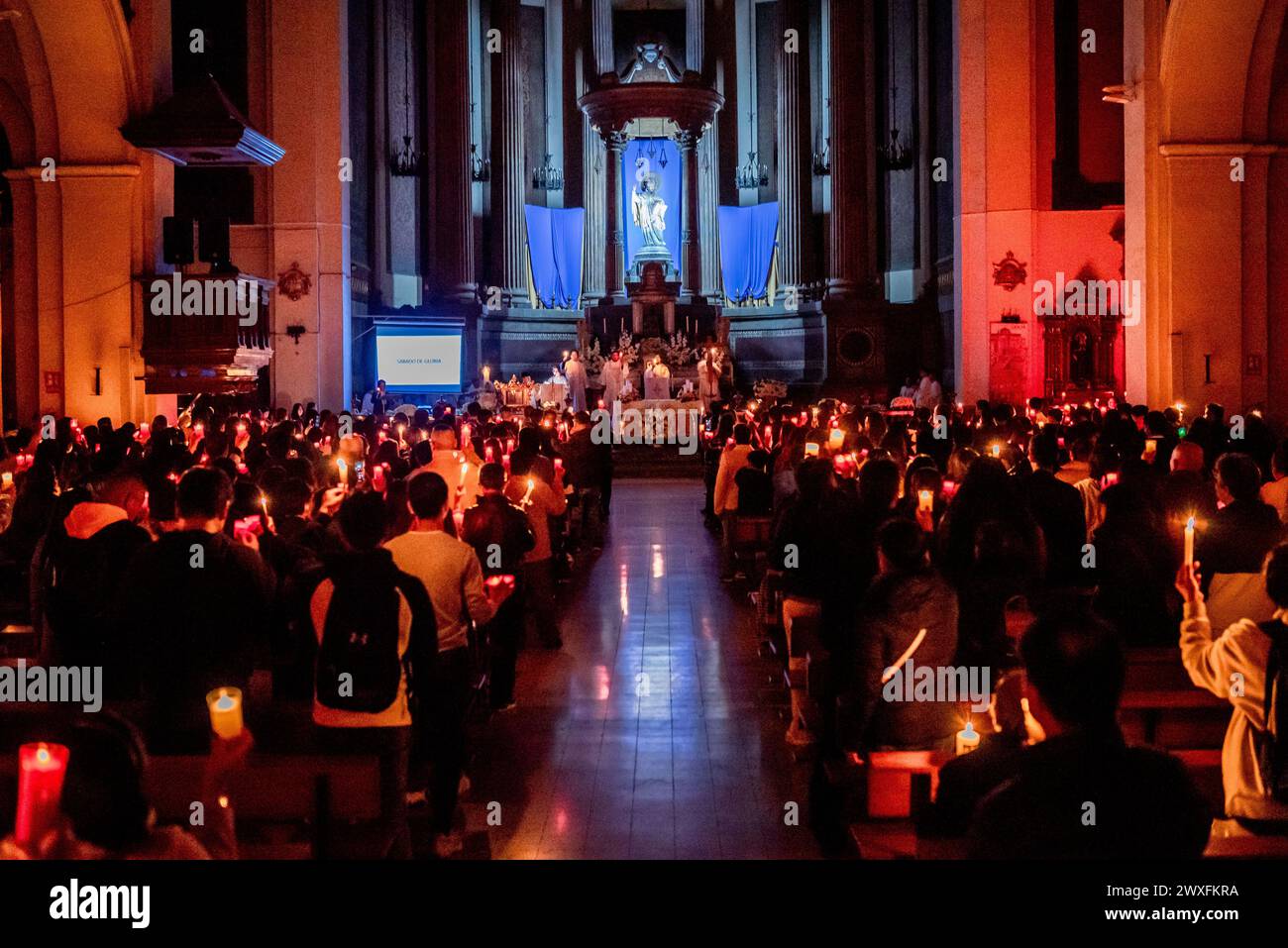 Barcelona, Spanien.30. März 2024, Barcelona, Spanien: An diesem Karstsamstag halten Mitglieder der philippinischen Gemeinde Barcelona Kerzen während der feierlichen Ostervigil und des Segens des neuen Feuers in der Kirche Sant Agusti im Stadtteil Raval im Rahmen der Feierlichkeiten der Karwoche. Quelle: Jordi Boixareu/Alamy Live News Stockfoto