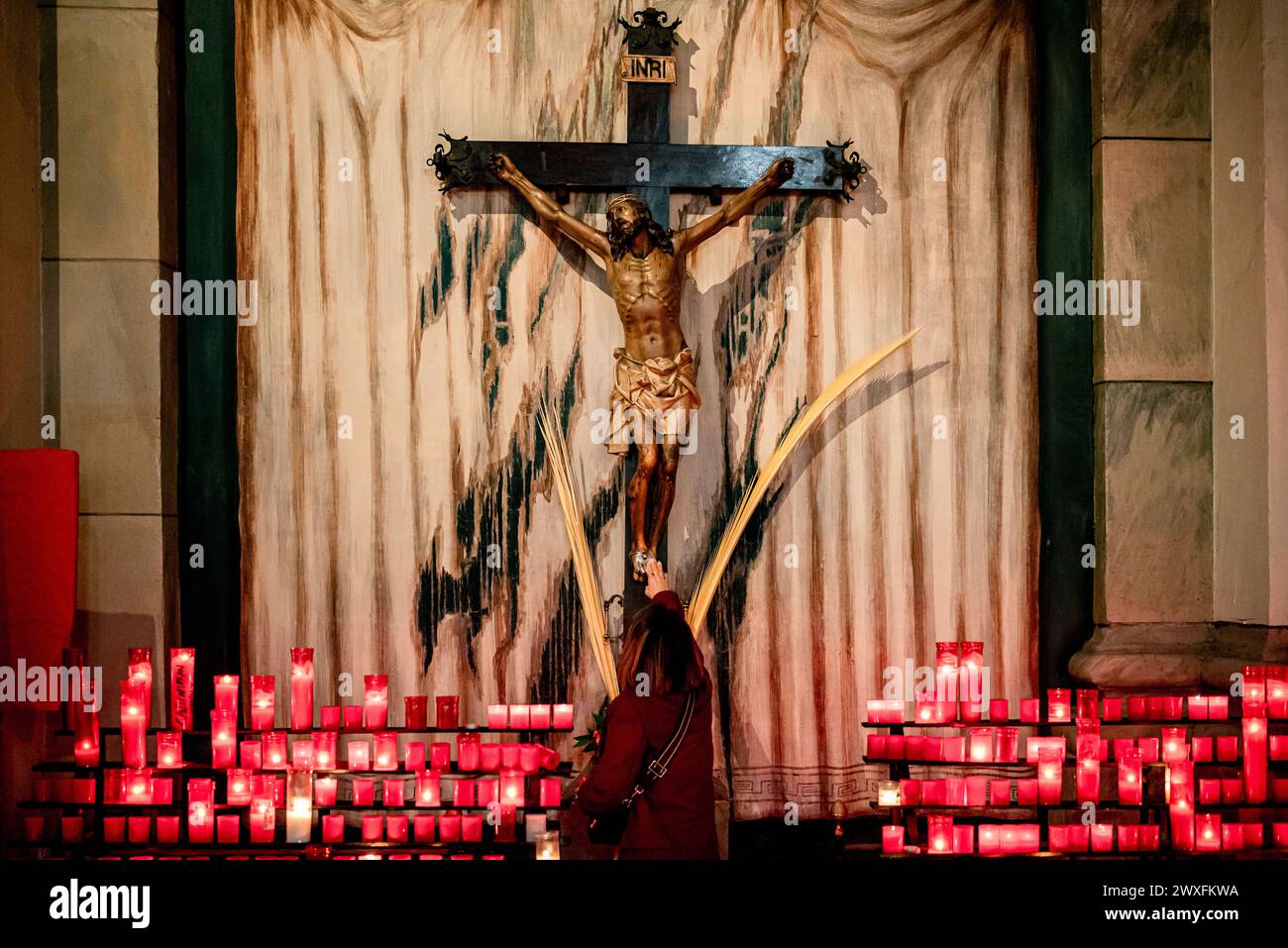 30. März 2024, Barcelona, Spanien: An diesem Heiligen Samstag berührt eine anbetende Frau die Füße einer Statue Jesu Christi in der Kirche Sant Agusti im Stadtteil Raval von Barcelona. Stockfoto