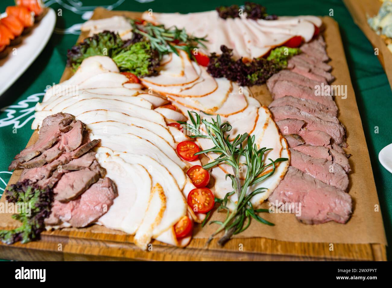 Eine köstliche Auswahl an Aufschnitt, einschließlich truthahnscheiben und Roastbeef, garniert mit frischen Kräutern und Kirschtomaten. Stockfoto