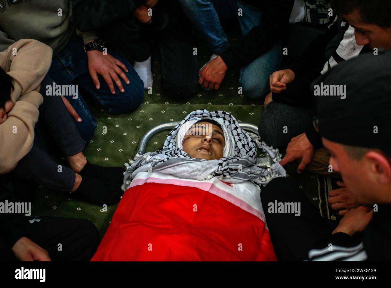 Jenin, Palästina. 30. März 2024. (ANMERKUNG DER REDAKTION: Bild zeigt den Tod) die Trauernden beten, während sie sich um den Körper von Mutasim Abu Abed, 13, während seiner Beerdigung in Qabatiya, nahe der Westjordanstadt Dschenin, sammeln. Dr. Fawaz Hamad, Direktor des Al-Razi Krankenhauses in Jenin, sagte dem lokalen Sender Awda TV, dass israelische Truppen Anfang Samstag einen 13-jährigen Jungen im nahegelegenen Qabatiya getötet haben. Das israelische Militär sagte, der Vorfall werde geprüft. Quelle: SOPA Images Limited/Alamy Live News Stockfoto