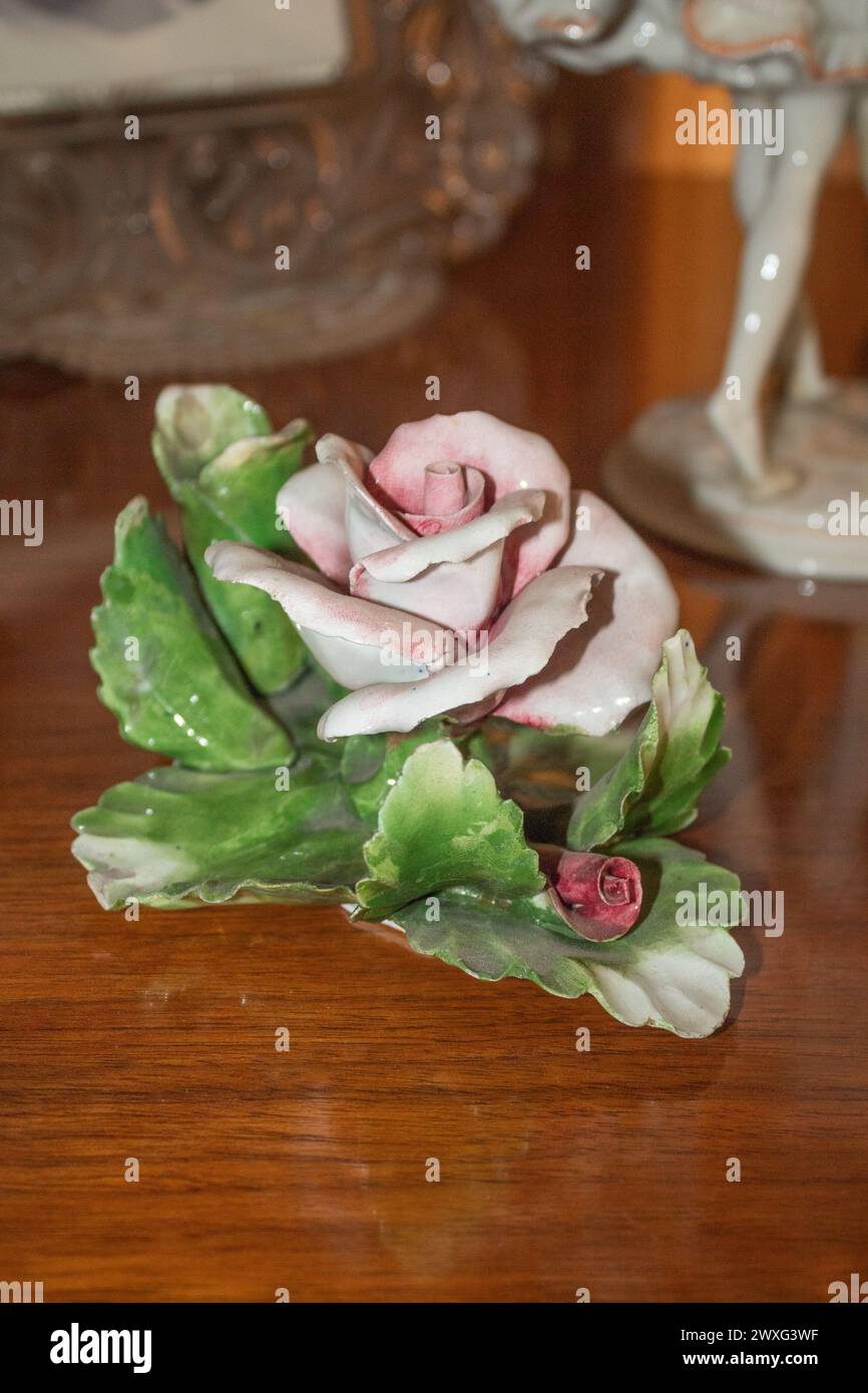 Glänzende rosafarbene Keramikblume mit verschwommenen femininen Verzierungen auf hölzernem Hintergrund Stockfoto