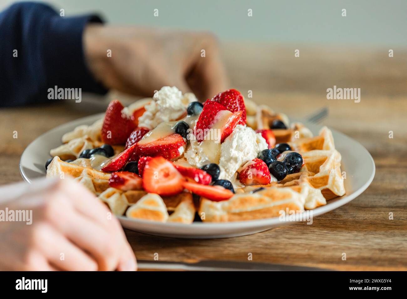 Goldene belgische Waffeln mit Erdbeeren, Heidelbeeren und frisch geschlagener Sahne. Ein köstlicher Genuss bei jedem Happen für ein besonderes Frühstück. Stockfoto