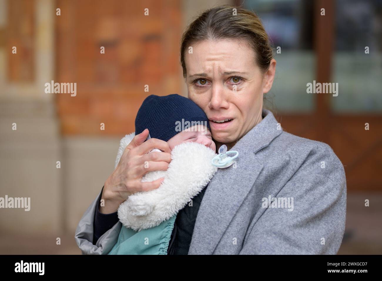 Porträt einer extrem erschöpften und gestressten Mutter in ihren 40ern, die ihr neugeborenes Baby hält und vor der Kamera weint Stockfoto