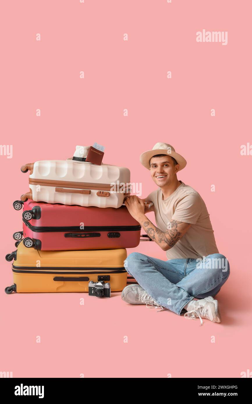 Junger männlicher Tourist mit vielen Koffern auf rosa Hintergrund Stockfoto