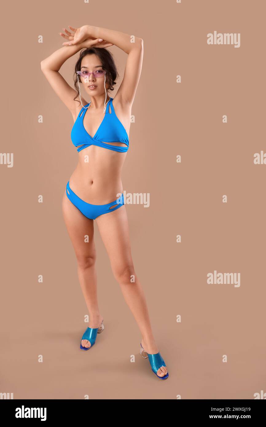 Sexy junge Frau im Badeanzug auf beigefarbenem Hintergrund Stockfoto