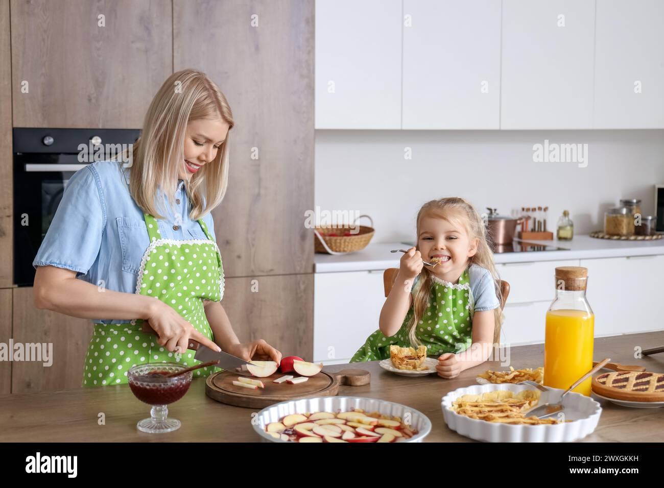 Süßes kleines Mädchen und ihre Mutter schneiden Apfel für Kuchen in der Küche Stockfoto