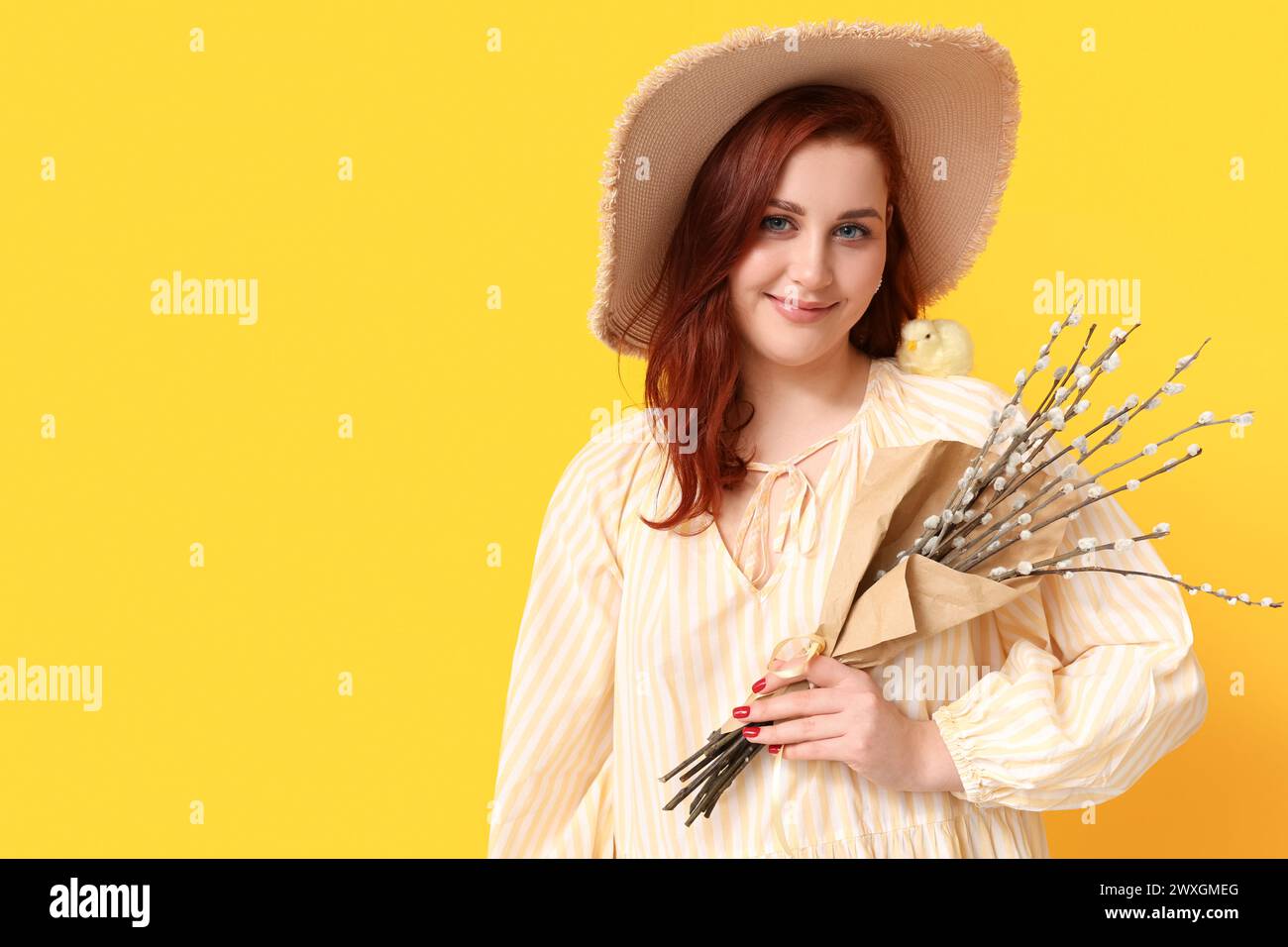 Schöne junge Frau mit Muschi Weidenzweigen und Küken auf gelbem Hintergrund. Osterfeier Stockfoto