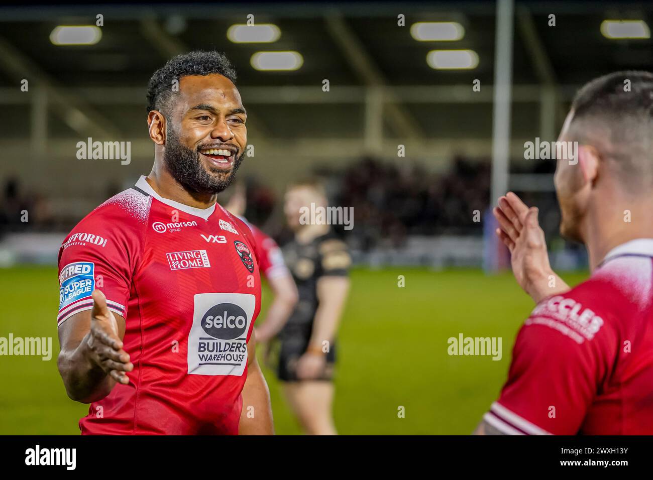 Salford, Manchester, Großbritannien. 30. März 2024. Super League Rugby: Salford Red Devils gegen Leigh Leoparden im Salford Community Stadium. KING VUNIYAYAWA ist glücklich mit dem Sieg und geht auf die High Five CADE CUST. James Giblin/Alamy Live News. Stockfoto