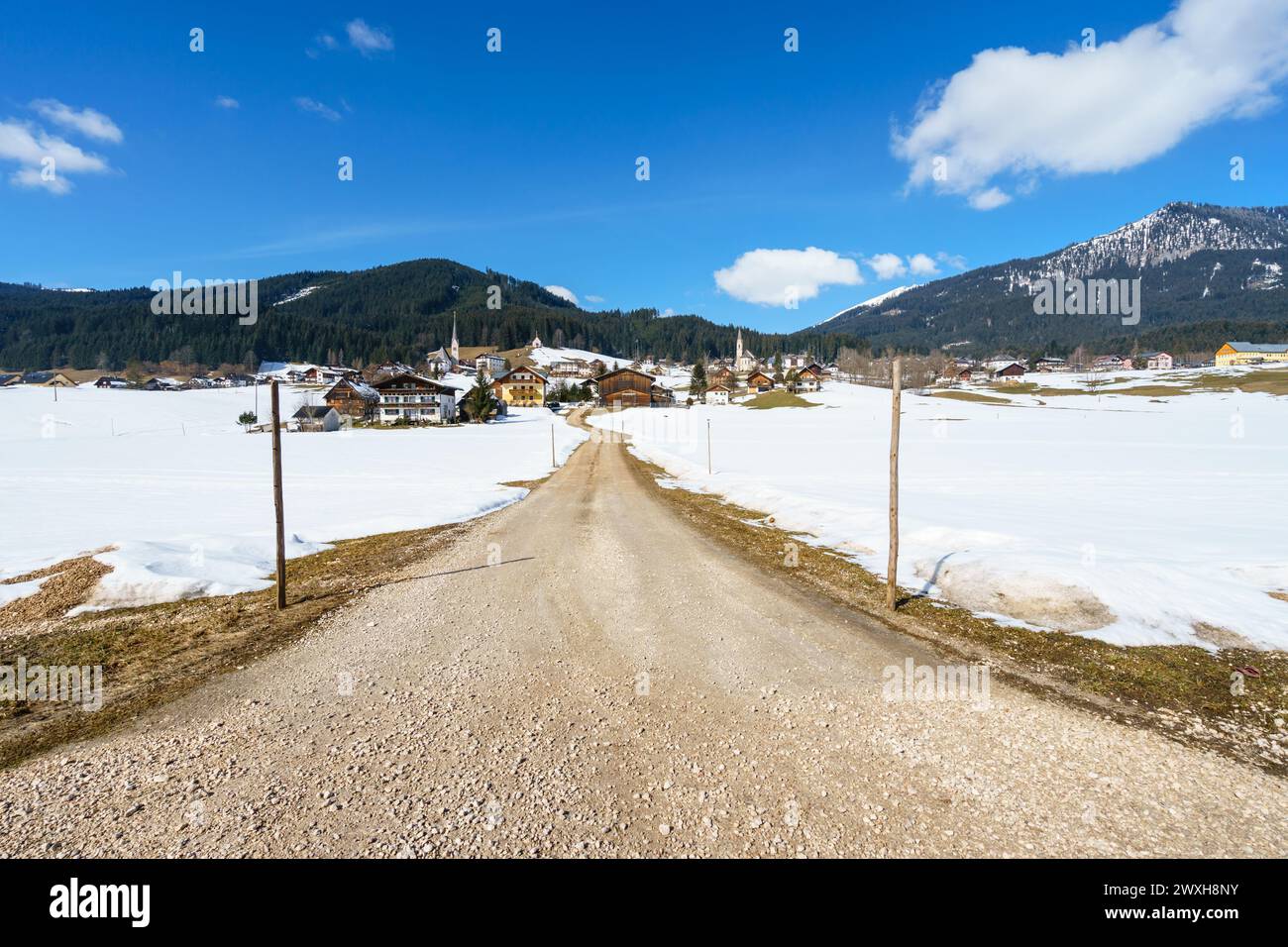 Ein schneebedecktes alpines Dorf mit einer unbefestigten Straße, die durch die Landschaft führt Stockfoto