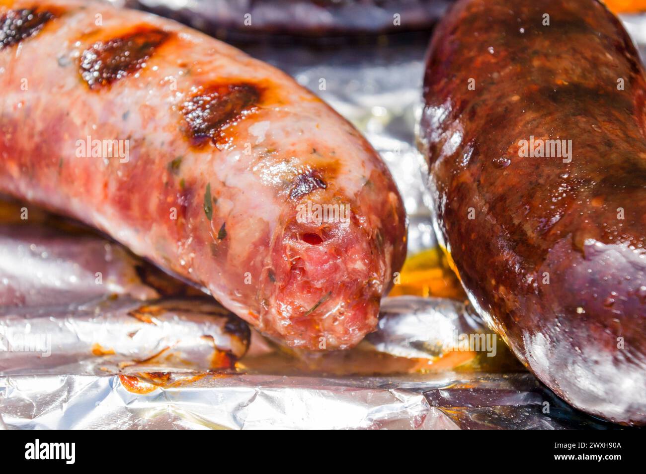 Zwei Hotdogs auf Folie, einer mit geschmolzenem Käse Stockfoto