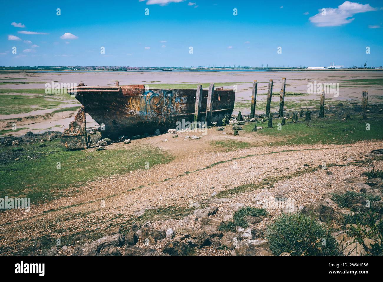 Ein altes, rostiges Boot an einem Flussufer bei Ebbe. Stockfoto