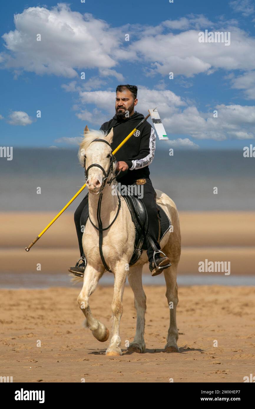 Altes Kavallerie-Spiel „Zelt-Pegging“ Reiter in Southport, Merseyside, 31.03.2024. Eine Gruppe von Männern spielt ihren Lieblingssport am Strand von Southport in der wunderschönen Ostersonne. Das Spiel, in Pakistan auch als Neza Bazi bekannt, ist eine Reitersportart uralten Ursprungs und ist eine von nur zehn von der International Equestrian Federation offiziell anerkannten Reitdisziplinen. Quelle: Cernan Elias/Alamy Live News Stockfoto