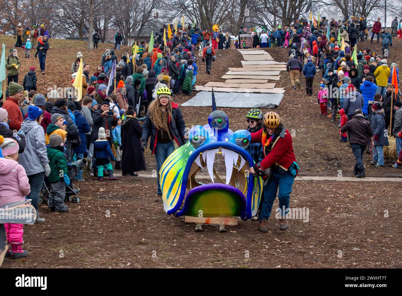 Drei Teilnehmer mit ihrem skurrilen Meeresbewohner mit drei Augen Schlitten bei der Jänner Powderhorn Park Art Sled Rally in Minneapolis, Minnesota. Bec Stockfoto