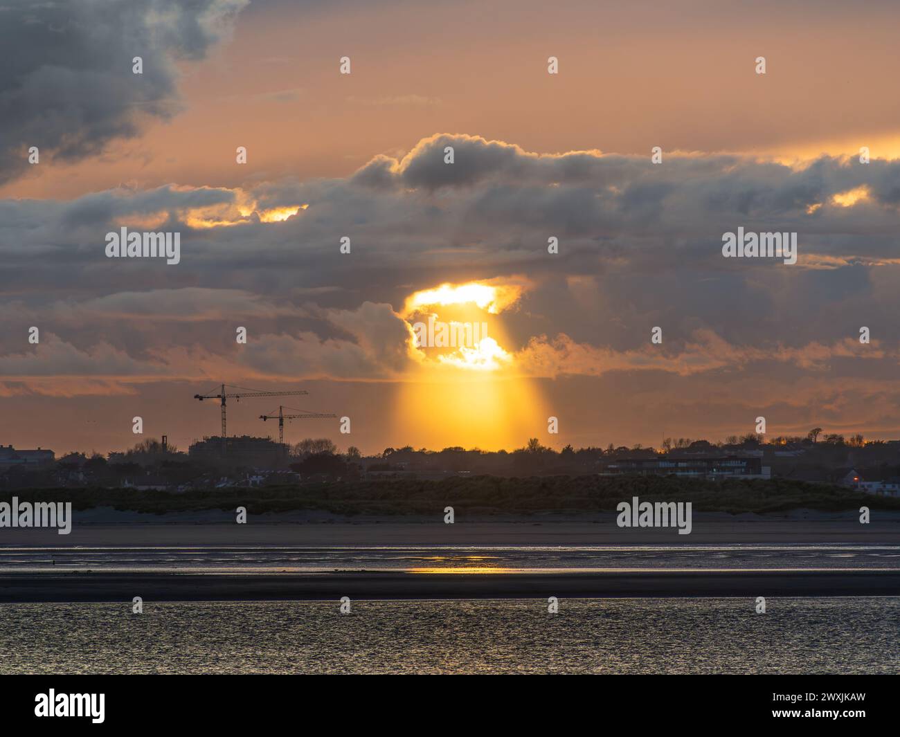 Sonnenuntergangslicht, das über Sutton Strand von einem leichten Bruch in den Wolken herabstrahlt Stockfoto