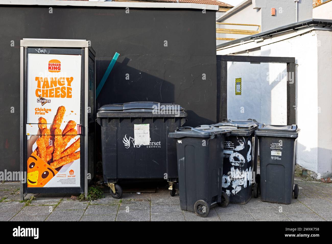 Eine Straßenszene mit einer Telefonzelle und einer Reihe von Mülltonnen in Weston-super-Mare, Großbritannien Stockfoto