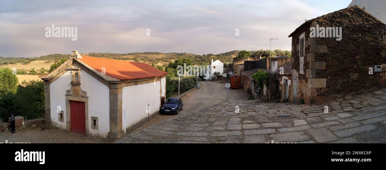 Kapelle von São Dâmaso, Panoramablick auf die kopfsteingepflasterte Straße am Rande des historischen Dorfes mit typischen Steinhäusern, Idanha-a-Velha, Portugal Stockfoto