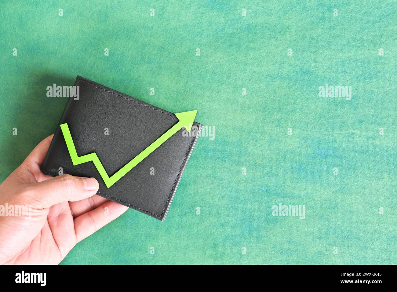 Männliche Hand, die eine Brieftasche mit grünem Pfeil nach oben hält. Konzept für Einsparungen und Investitionswachstum. Stockfoto