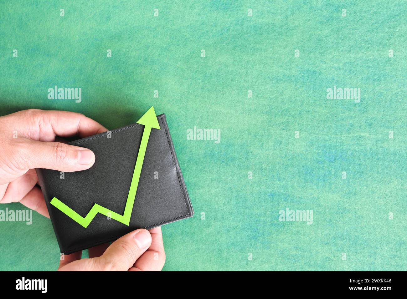 Männliche Hand, die eine Brieftasche mit grünem Pfeil nach oben hält. Konzept für Einsparungen und Investitionswachstum. Stockfoto