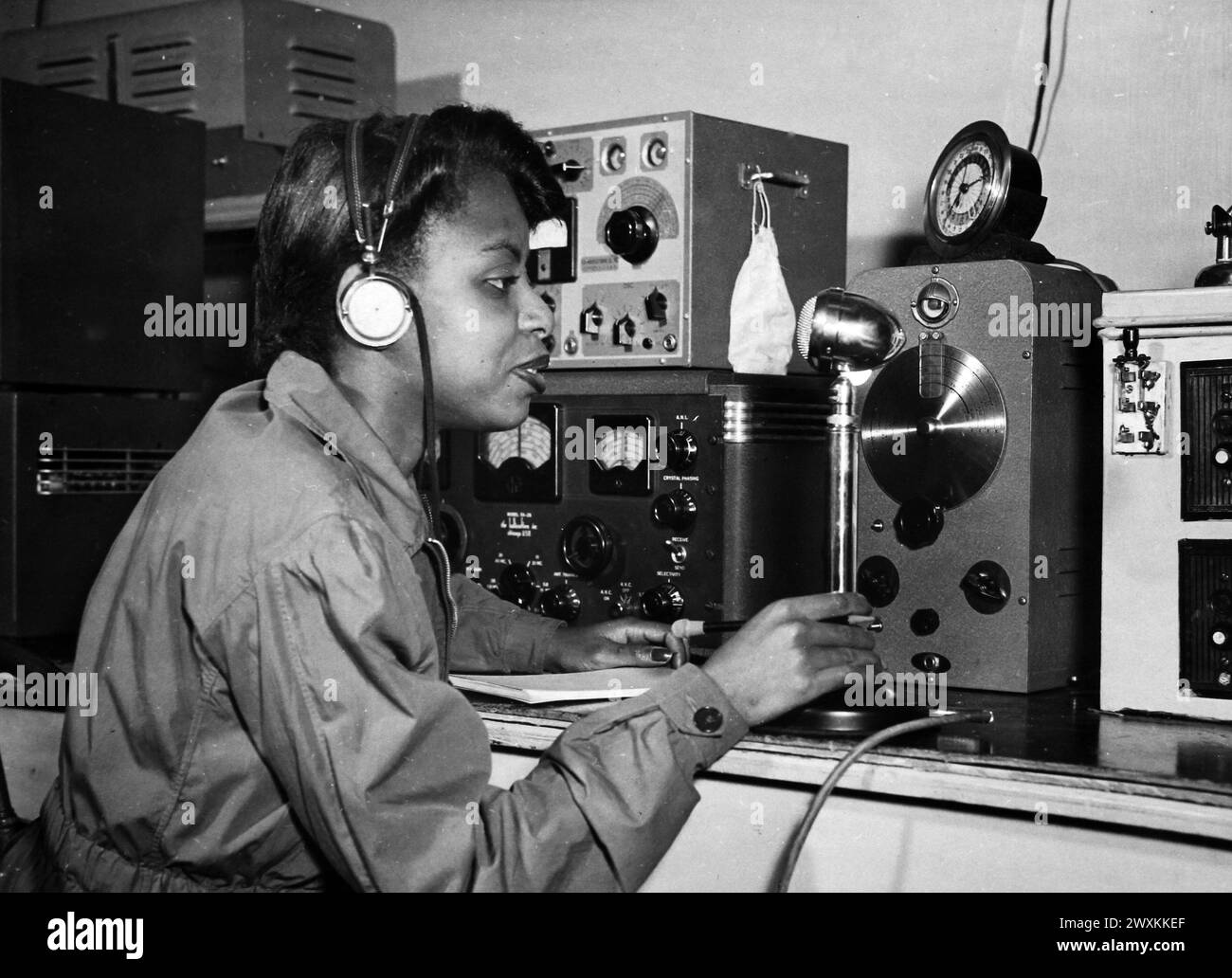 Dieses Foto zeigt eine junge Frau, die die Reparaturen an einem Radio in einer Werkstatt der Nationalen Jugendverwaltung ca. prüft. 1939-1943 Stockfoto