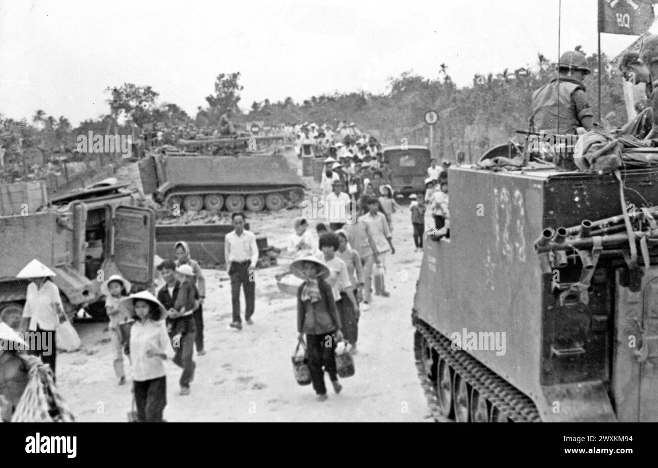 Vietnam-Krieg: M-113 gepanzerte Personalträger stehen bereit, während vietnamesische Flüchtlinge während der Tet-Offensive CA das Dorf My Tho in der Provinz Dinh Tuong evakuieren. 1968 Stockfoto