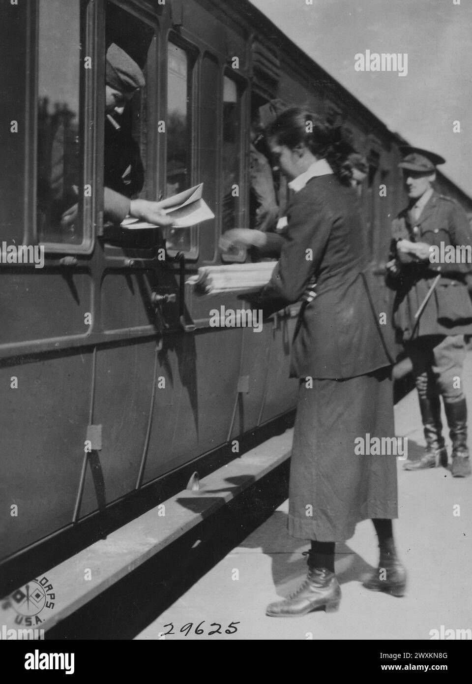 Ein englisches Nachrichtenmädchen verkauft Zeitungen an amerikanische Soldaten an Bord eines Truppenzuges Ca. 1918 Stockfoto