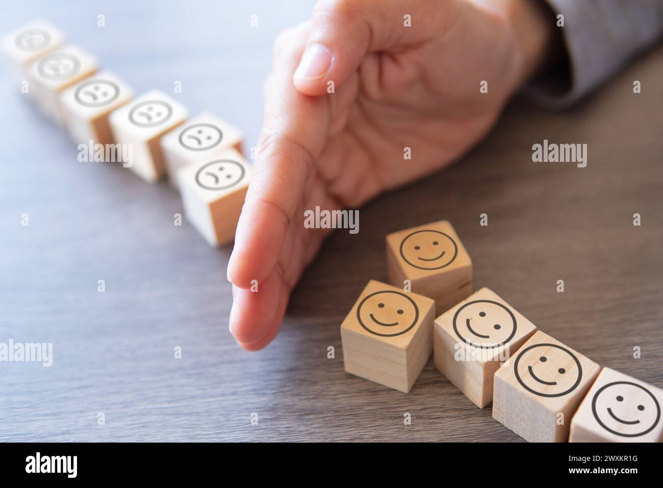 Die Hand trennt das Smile Face-Symbol vom Sad Face-Symbol. Vermeiden Sie das Konzept einer toxischen Person. Stockfoto