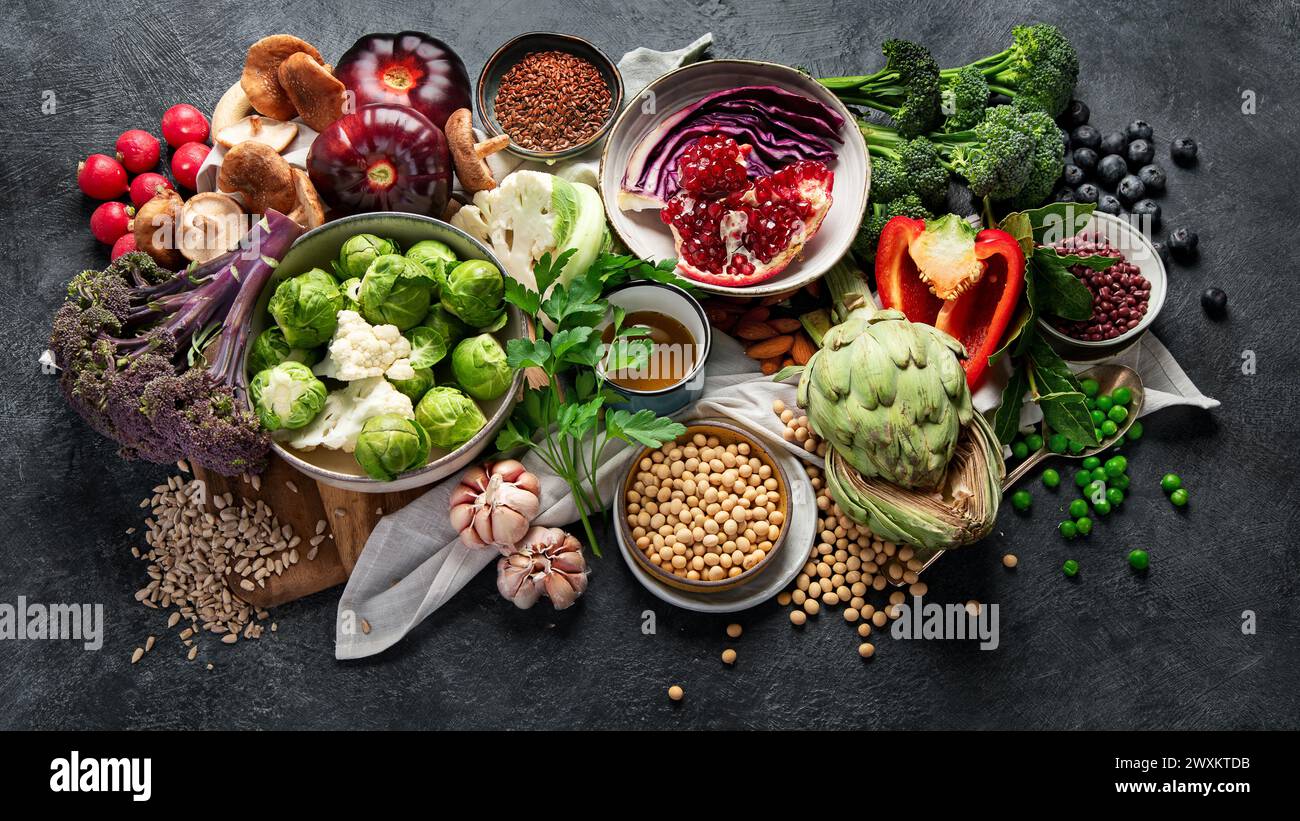 Veganes Essen. Pfeffer, Brokkoli, Kohl, Knoblauch, Pilze, Granatapfel auf dunklem Hintergrund. Draufsicht Stockfoto