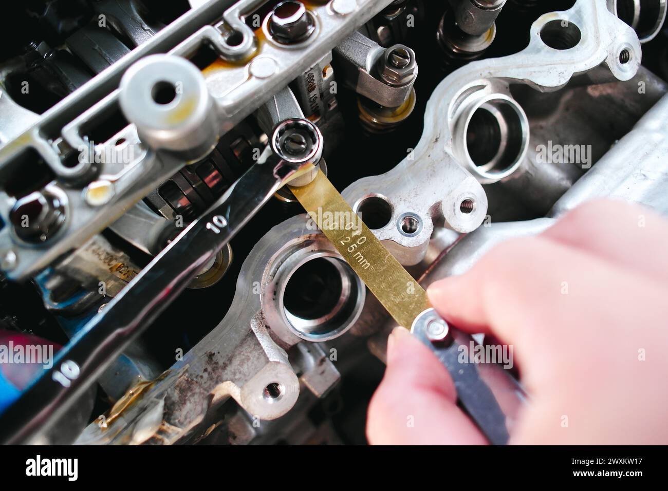 Kfz-Mechaniker prüfen und einstellen Ventile des Kfz-Motors mit Fühlerlehre oder Dickenmessgerät, Kfz-Wartungskonzept Stockfoto