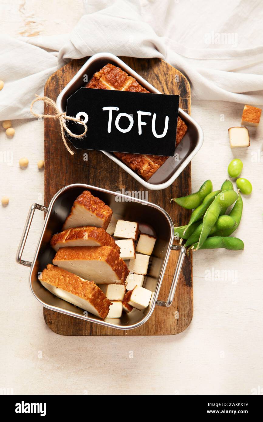 Soja-Lebensmittel. Gebackener Tofu-Käse auf einem Brett, Sojabohnen. Veganes Produkt. Draufsicht Stockfoto