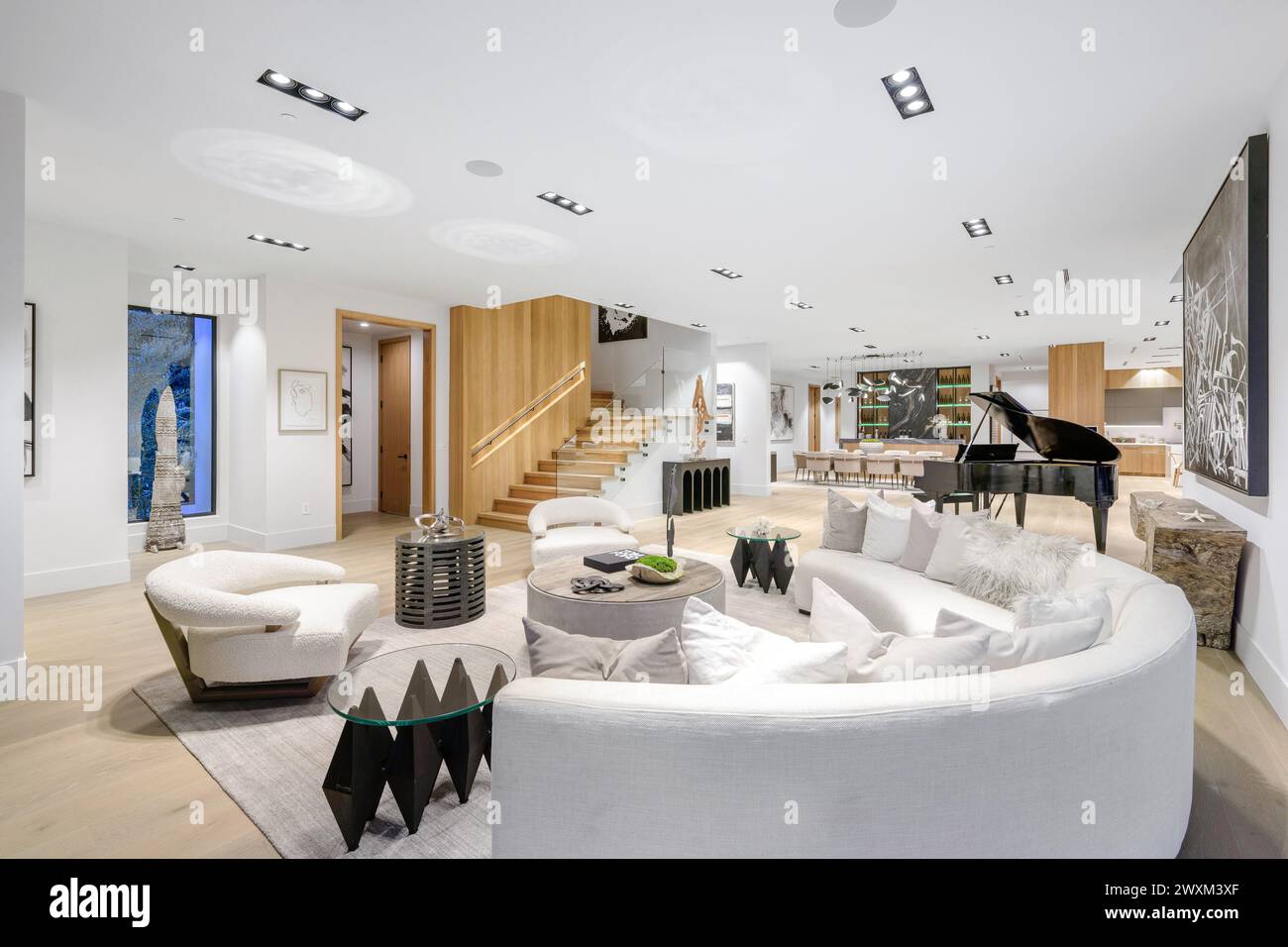 Ein weißes Sofa, zwei schwarze Stühle und ein Klavier im Zimmer. Stockfoto