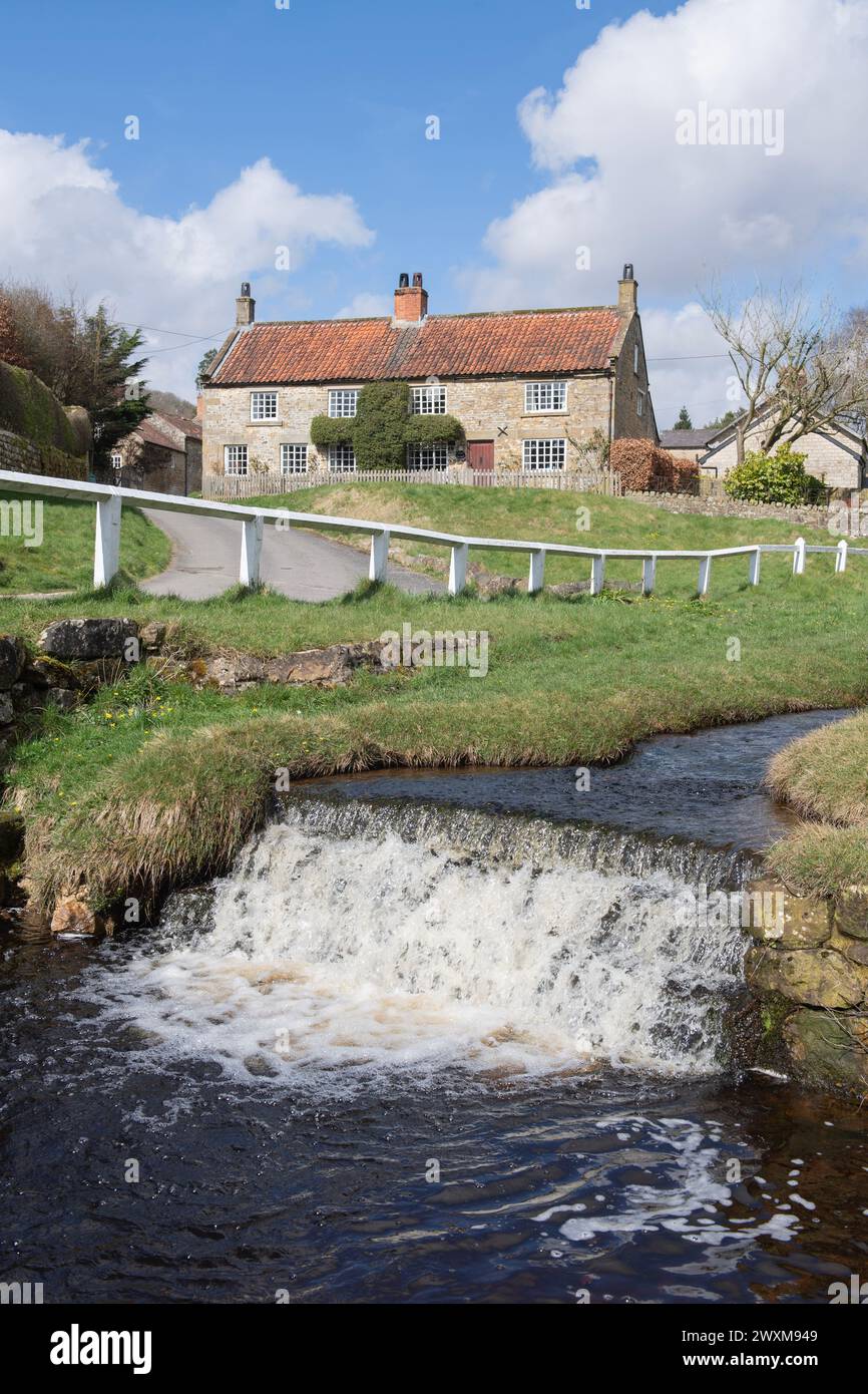 Ein traditionelles Steinhaus am Fluss im malerischen Dorf Hutton-le-Hole im North York Moors National Park Stockfoto