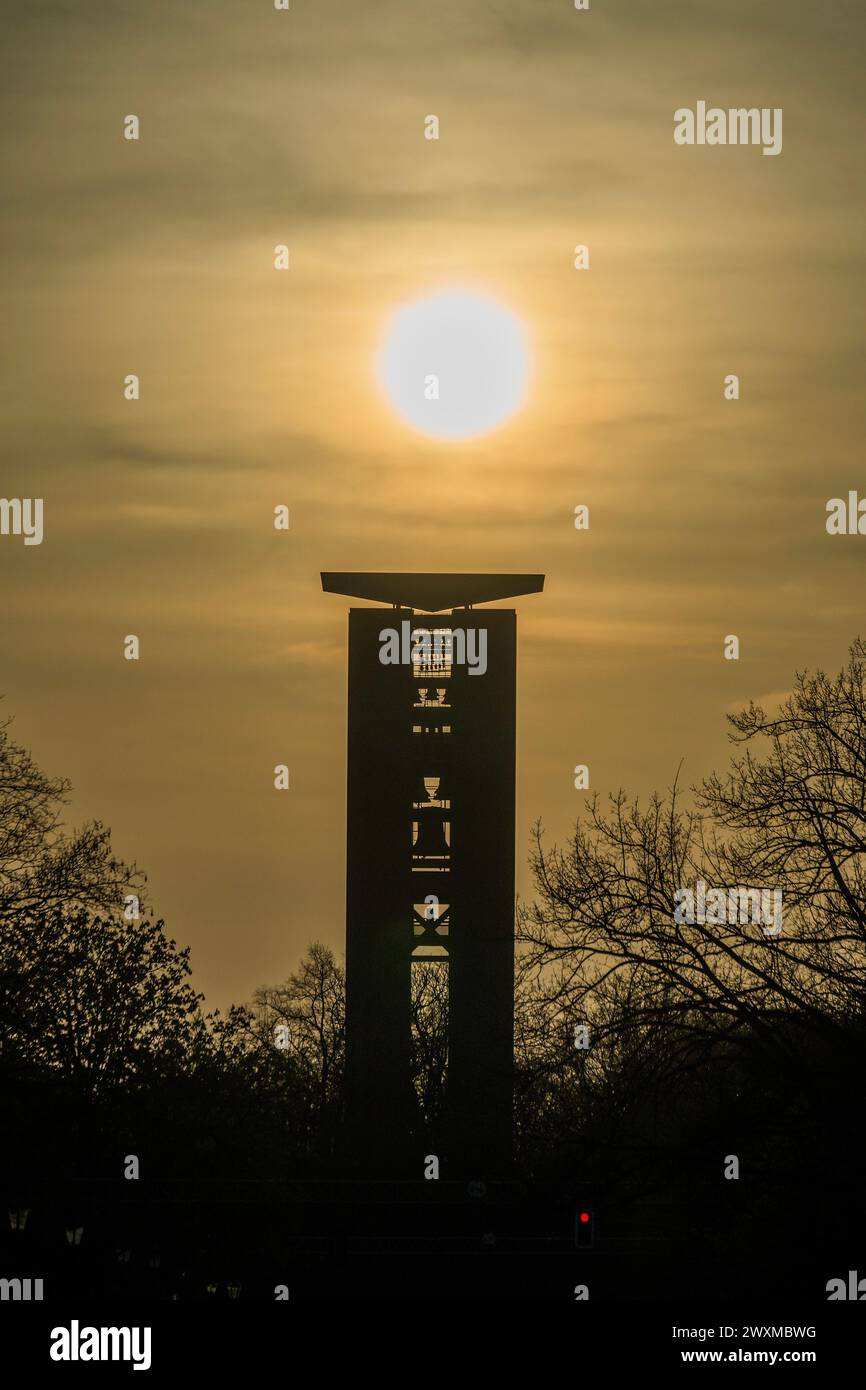 Berlin, Deutschland. 31. März 2024. Das Carillon in Berlin-Tiergarten ist ein großes, manuell gespieltes Konzertinstrument, bestehend aus 68 Glocken, einem Gewicht von insgesamt 48 Tonnen, das mit einer Tastatur von 5 1/2 vollchromatischen Oktaven verbunden ist. Die größte Glocke wiegt 7,8 Tonnen. Das Carillon wurde von der Königlich-niederländischen Gießerei Eijsbouts nach den Spezifikationen von Jeffrey Bossin gegossen. Es ist eines der größten Instrumente seiner Art in Europa. Der Carillonneur sitzt in einer Spielkabine mitten in den Glocken und spielt mit Fäusten und Füßen auf einer Schlagstock-und-Pedal-Tastatur. Die Sonne untergeht über der Stadt Stockfoto