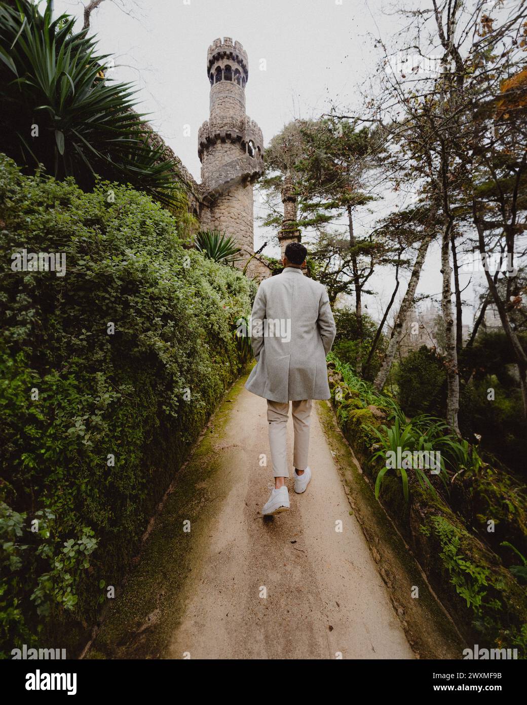 Ein Mann in formeller Kleidung, der auf einen hohen Turm zugeht Stockfoto