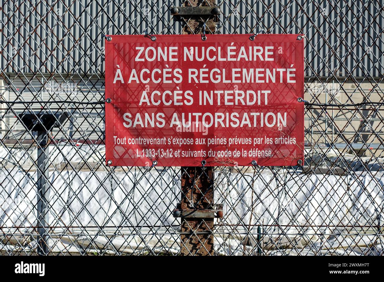 Rotes Warnschild auf Französisch auf Metallzaun, das den Zugang zu einer sicheren Atomzone einer abgezäunten Industrie- oder Militäranlage in Chooz einschränkt Stockfoto
