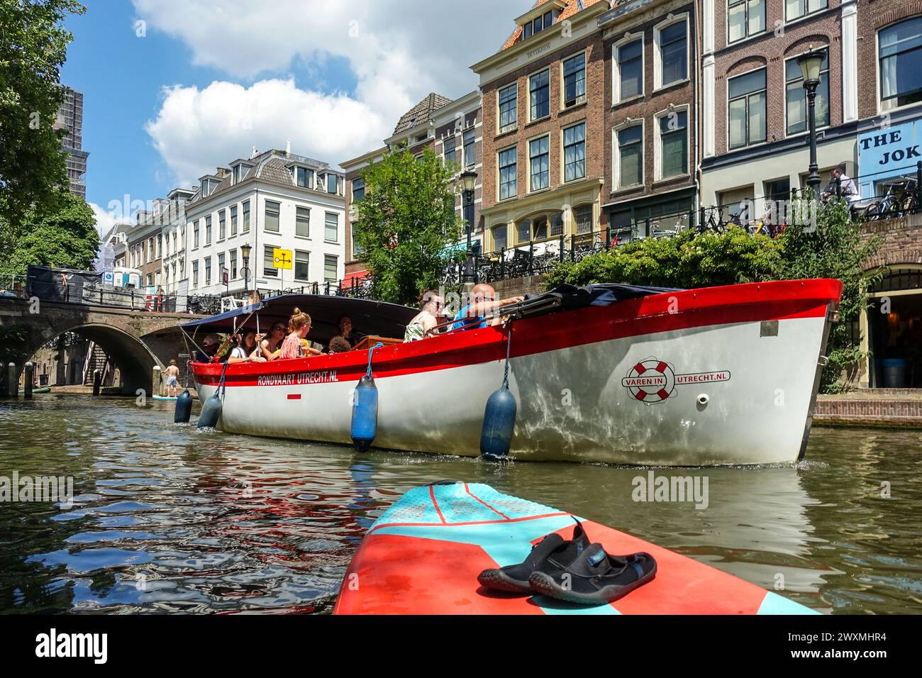 Touristenboot, das an einem sonnigen Tag in den Niederlanden entlang eines malerischen Kanals im Zentrum von Utrecht fährt, umgeben von historischen Gebäuden und Brücken Stockfoto