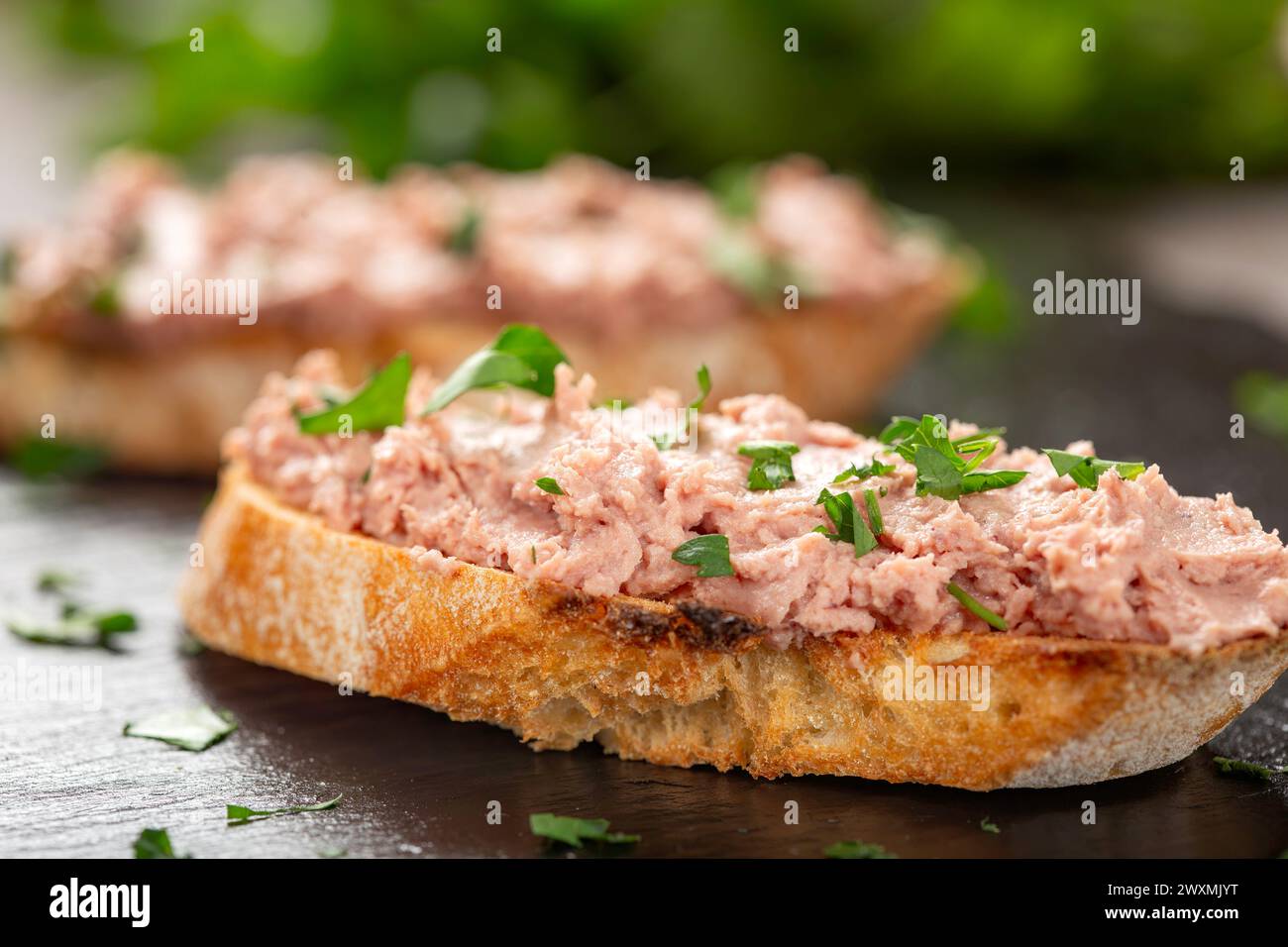Schweineplätzchen auf geröstetem Brot mit frischen Kräutern - Nahaufnahme. Stockfoto