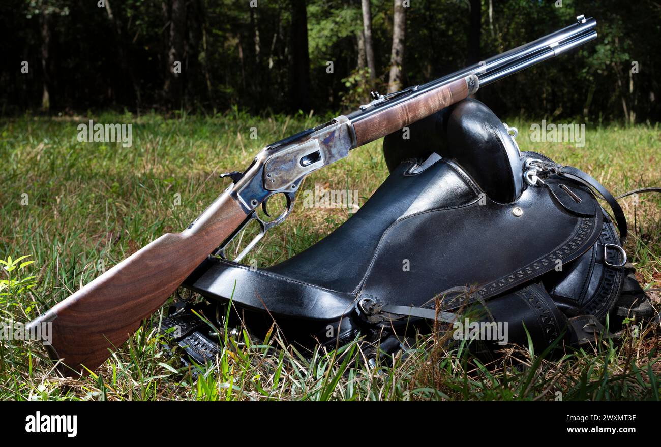 Ein Akkugewehr im Cowboy-Stil, das auf einem Sattel in einem grünen Wald ruht. Stockfoto