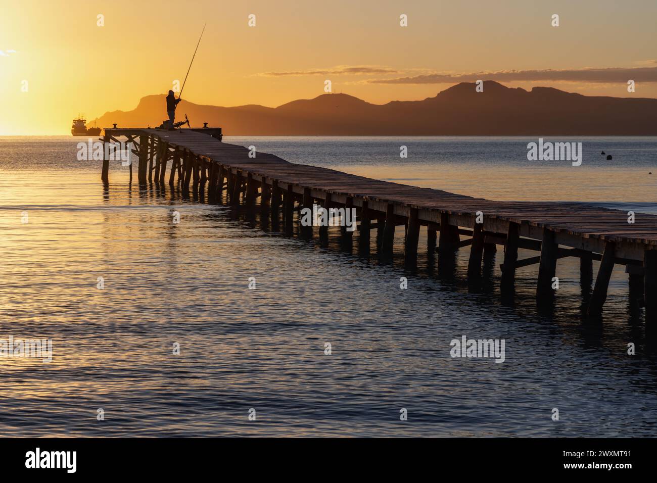 Fischer auf Holzsteg bei Sonnenaufgang in der Bucht von Port d'Alcudia auf Mallorca Stockfoto
