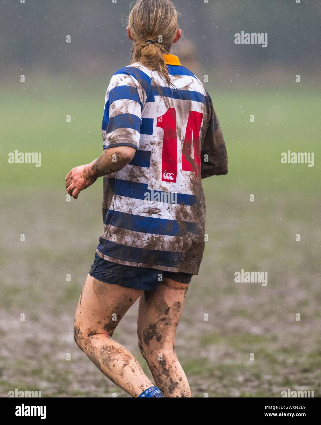 Englische Amateur-Rugby-union-Frauen spielen unter nassen und matschigen Bedingungen und ein Nummer 14-Trikot. Stockfoto