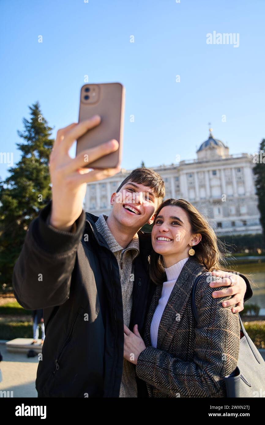 Ein junges Paar besucht den Königspalast in Madrid und macht ein Selfie mit ihren Smartphones Stockfoto