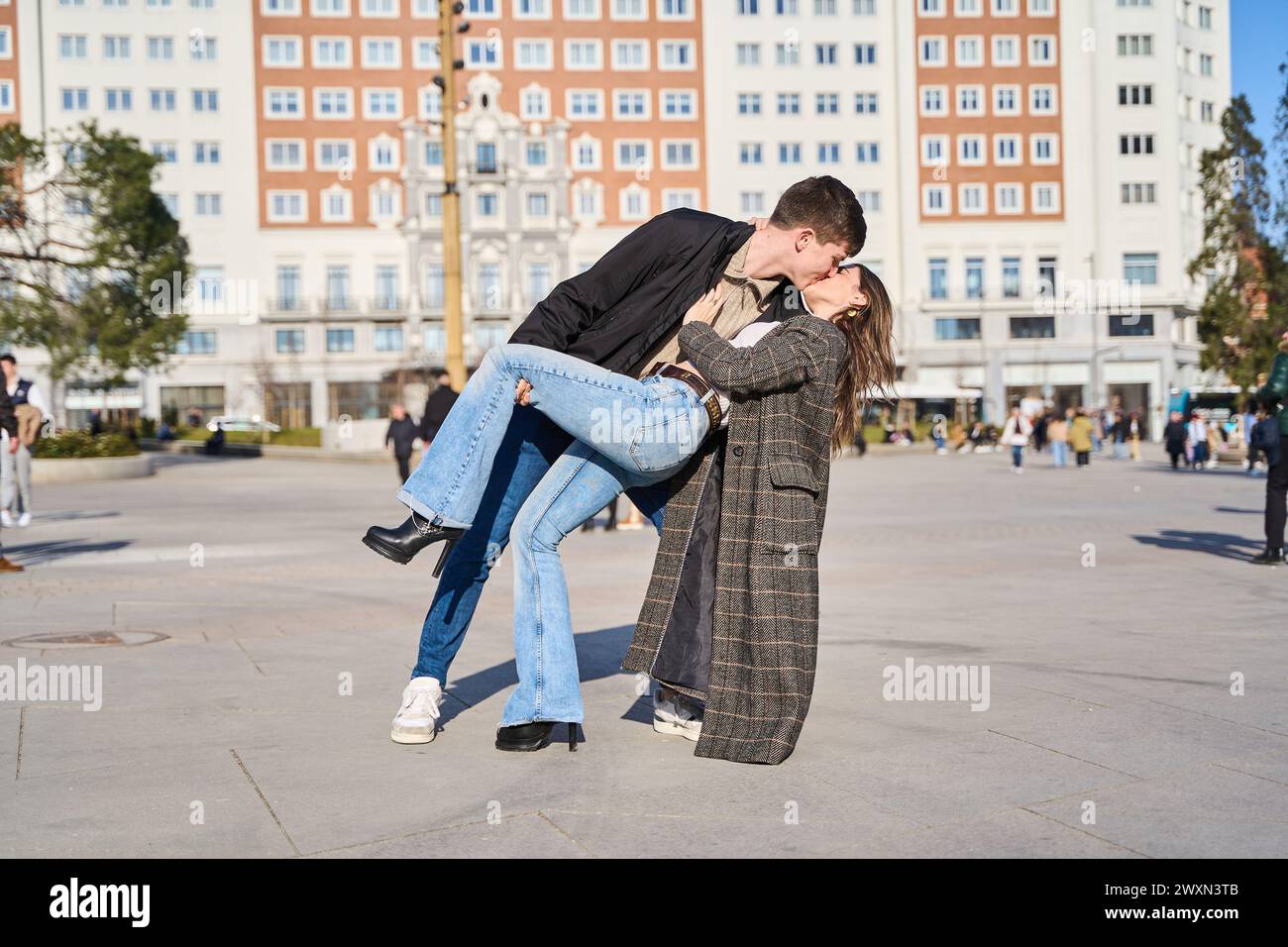 Das junge Paar tauchte in einen leidenschaftlichen Kuss ein, der Intensität und Romantik in der pulsierenden Stadt überträgt Stockfoto