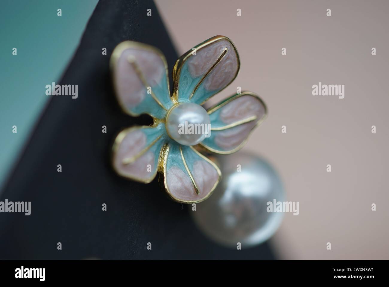 Ein eleganter Ohrring mit weißen Perlen, rosa Blüten, Gold und Silber Stockfoto