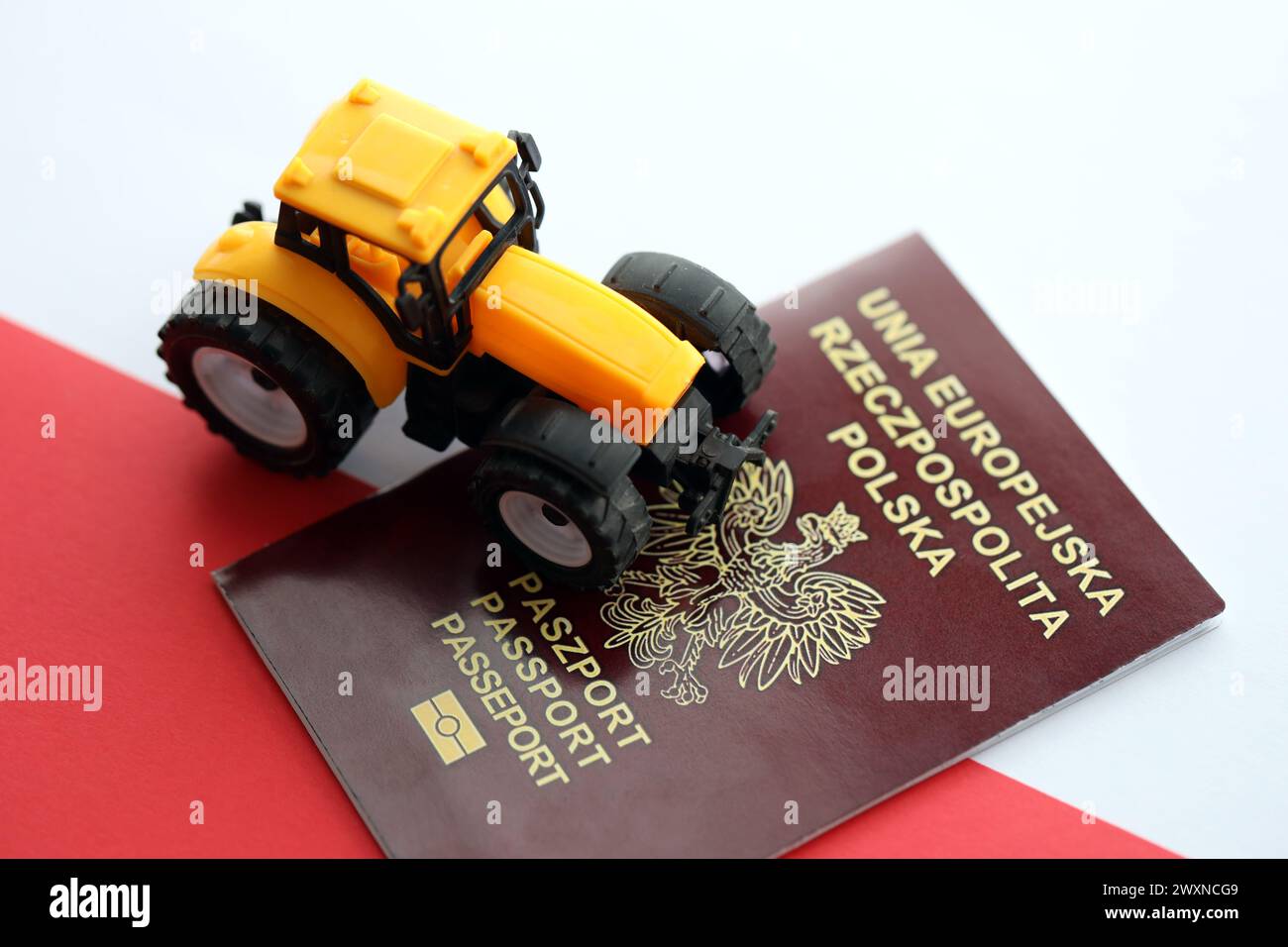 Roter polnischer Pass und gelber Traktor auf glatter rot-weißer Flagge von Polen Nahaufnahme Stockfoto