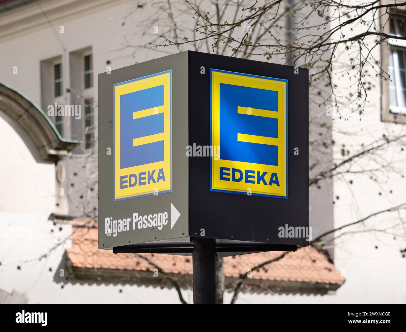 Edeka Rigaer Passage Schild des Lebensmitteleinzelhändlers. Deutsches Supermarkt-Logo mit einem Richtpfeil in Richtung Markt. Stockfoto