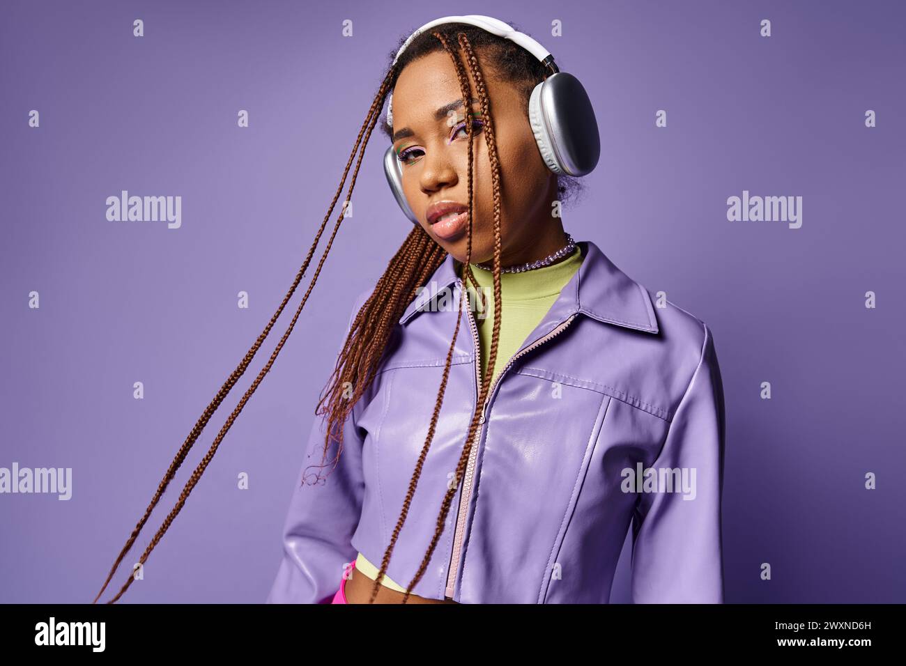 Junge afroamerikanische Frau mit Dreadlocks und schnurlosen Kopfhörern, die Musik in violettem Ton genießen Stockfoto