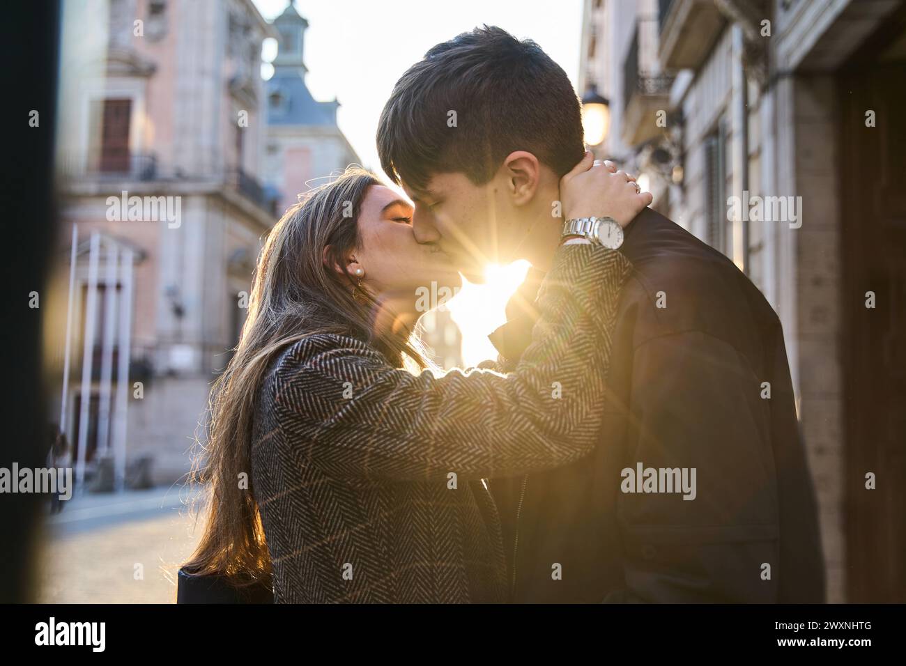 Zwei Liebende küssen sich bei Sonnenuntergang auf der Straße. Ein junges Paar verbringt den valentinstag als Paar. Stockfoto